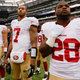 Colin Kaepernick and 49ers teammates stand during the national anthem in 2014. Photo credit: Julio Cortez/AP